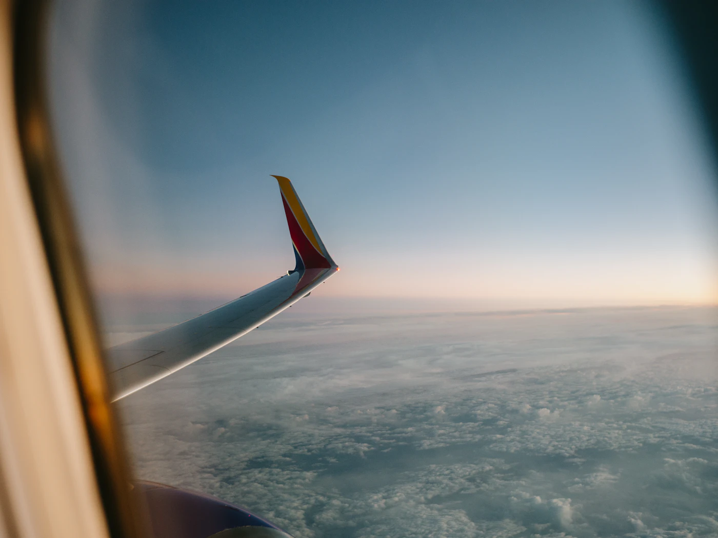 Airplane wing above the clouds at sunset